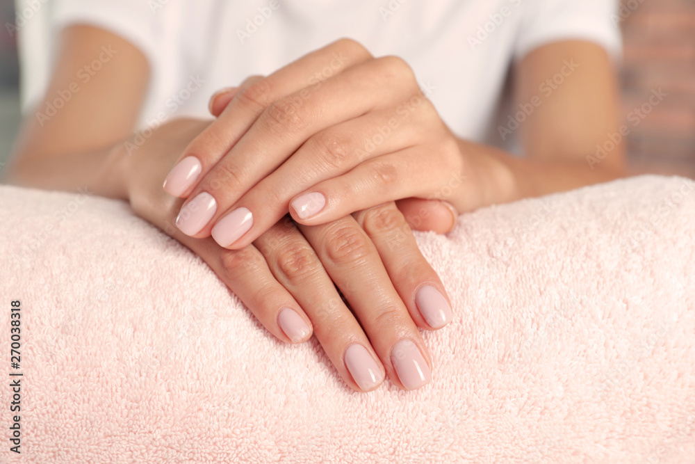 Woman showing neat manicure on towel, closeup. Spa treatment