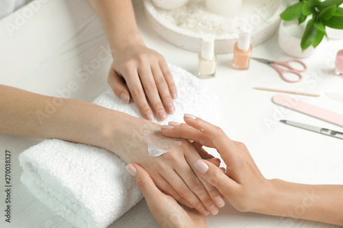 Cosmetologist applying cream on woman s hand at table in spa salon  closeup