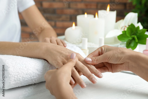 Cosmetologist massaging client s hand at table in spa salon  closeup