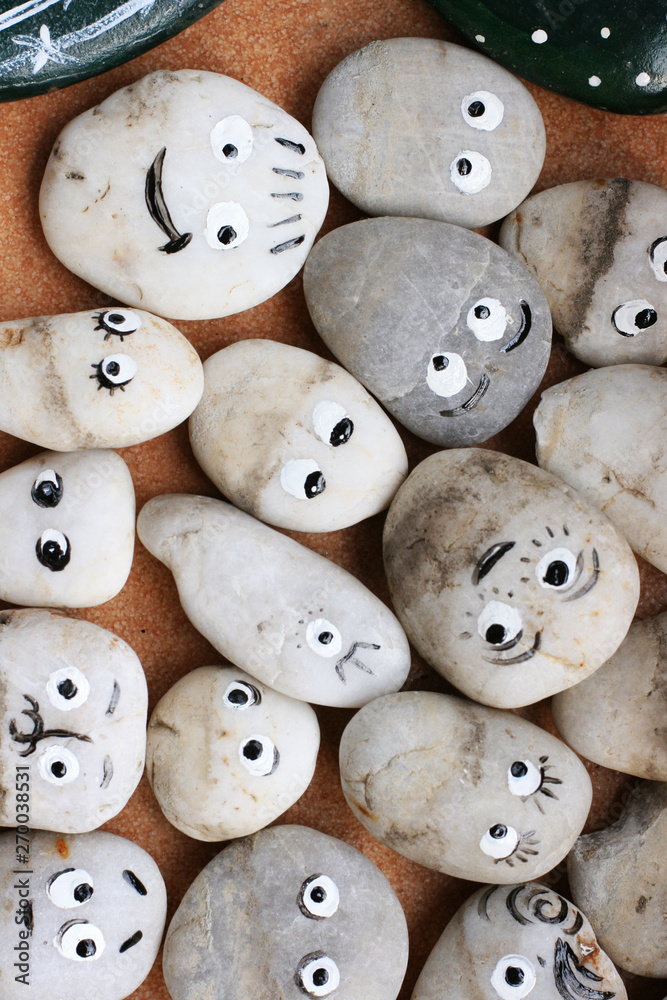 Stone decor for garden. Stones with funny faces. Allegory on society, group, friendship and teamwork Stone decor for garden. Stones with funny faces. Allegory on society, group, friendship and teamwork