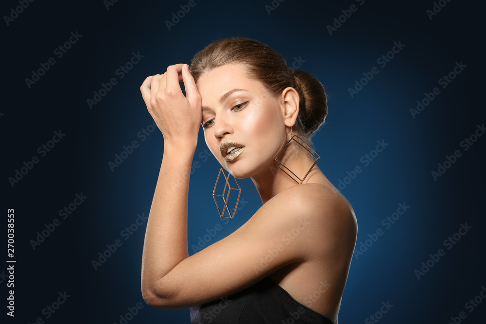 Fototapeta premium Portrait of beautiful lady with gold lipstick on color background