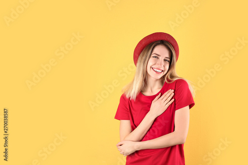 Portrait of woman holding hands near heart on color background. Space for text