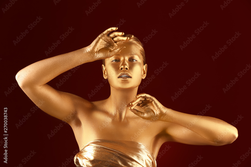 Portrait of beautiful lady with gold paint on skin against color background