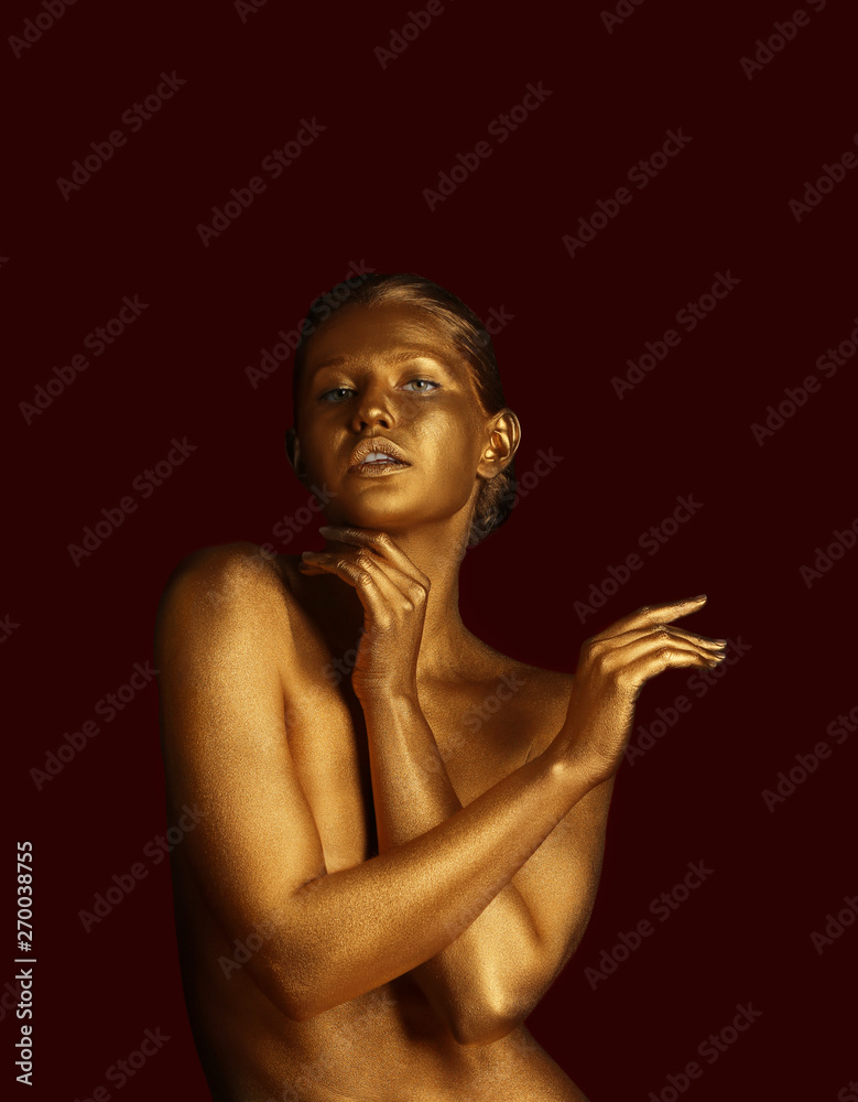 Fototapeta Portrait of beautiful lady with gold paint on skin against color background