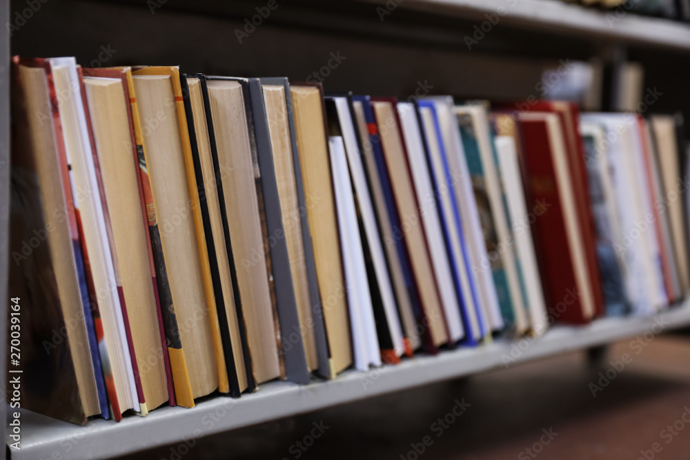 Collection of books on metal shelf in library Collection of books on metal shelf in library