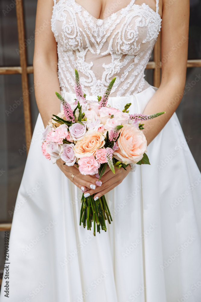 Beautiful wedding bouquet of white roses, lupine, peony in the hands of the bride on her wedding day Beautiful wedding bouquet of white roses, lupine, peony in the hands of the bride on her wedding day