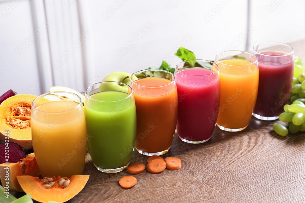 Glasses with different juices and fresh ingredients on wooden table Glasses with different juices and fresh ingredients on wooden table