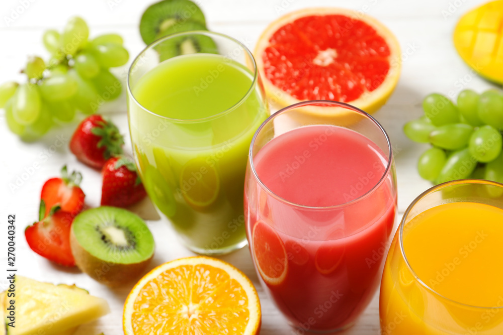 Glasses with different juices and fresh fruits on wooden table Glasses with different juices and fresh fruits on wooden table