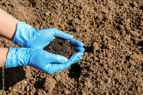 Scientist holding pile of soil above ground, closeup. Space for text