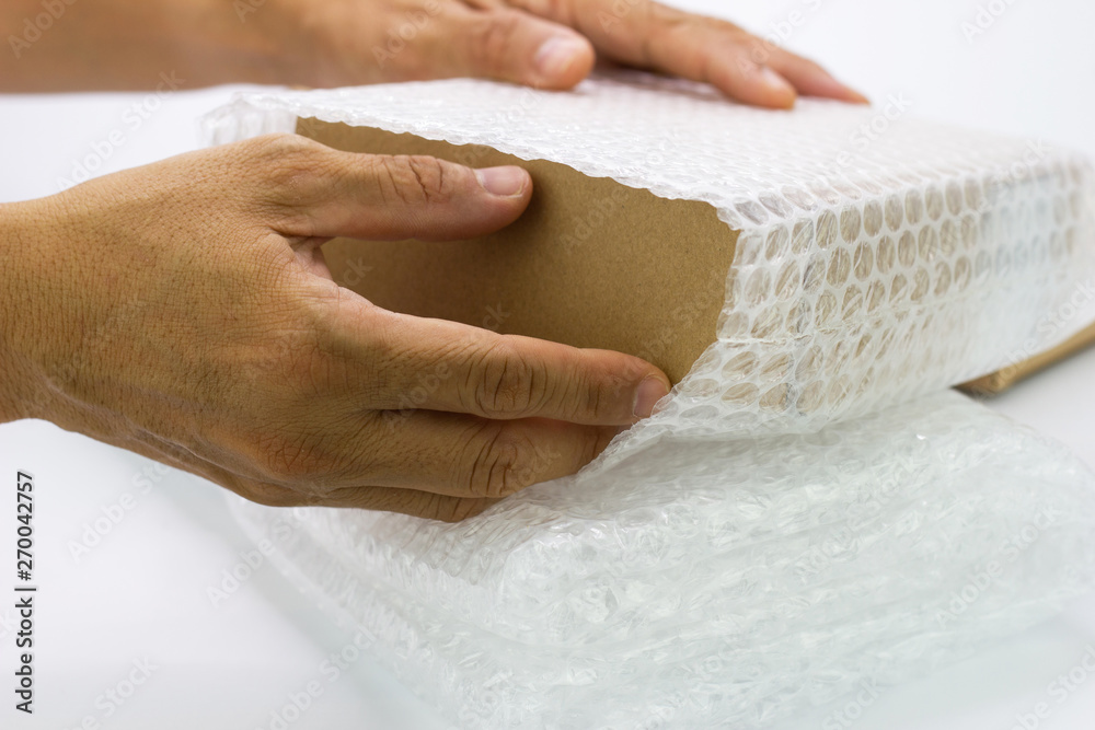 hand of man hold Bubbles covering the box by bubble wrap for protection product hand of man hold Bubbles covering the box by bubble wrap for protection product