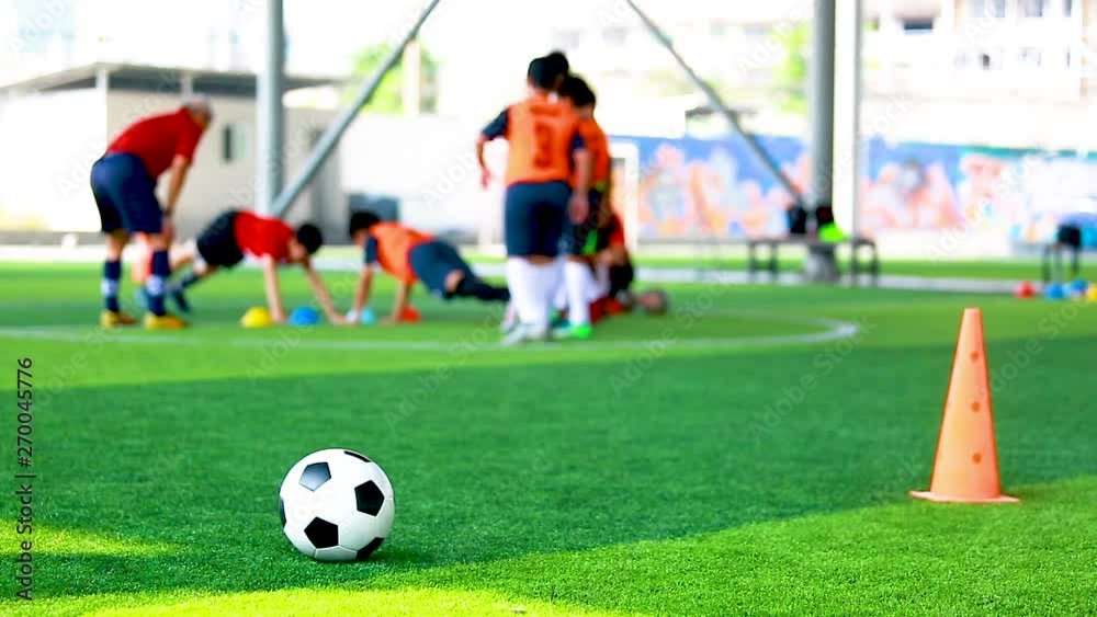 Soccer ball and cone marker on green artificial turf Soccer ball and cone marker on green artificial turf