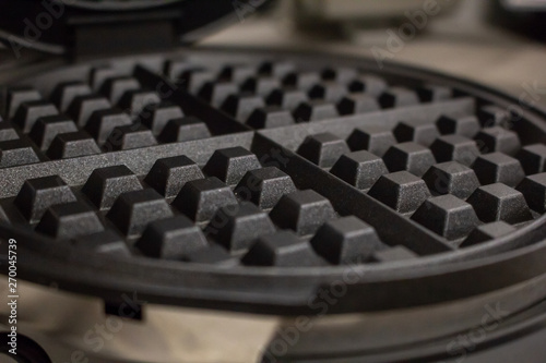 A closeup shot of a waffle iron and the common waffle pattern