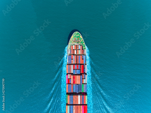 Aerial top view container ship full speed with beautiful wave pattern on the blue sea for logistics, import export, shipping or transportation.