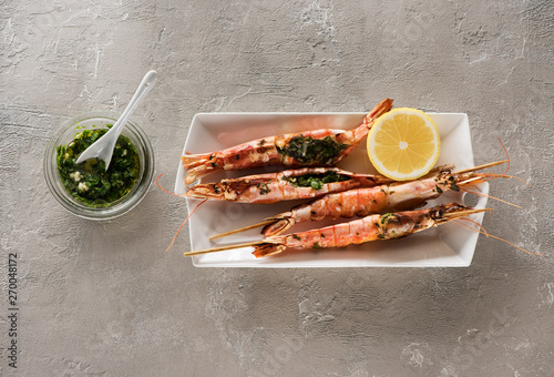 Seafood Shrimps Prawns skewers with marinade from garlic and herbs on a light concrete background, top view. Barbecue srimps prawns photo