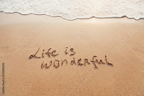 Life is wonderful, positive thinking concept. Inspirational quote written on sand.