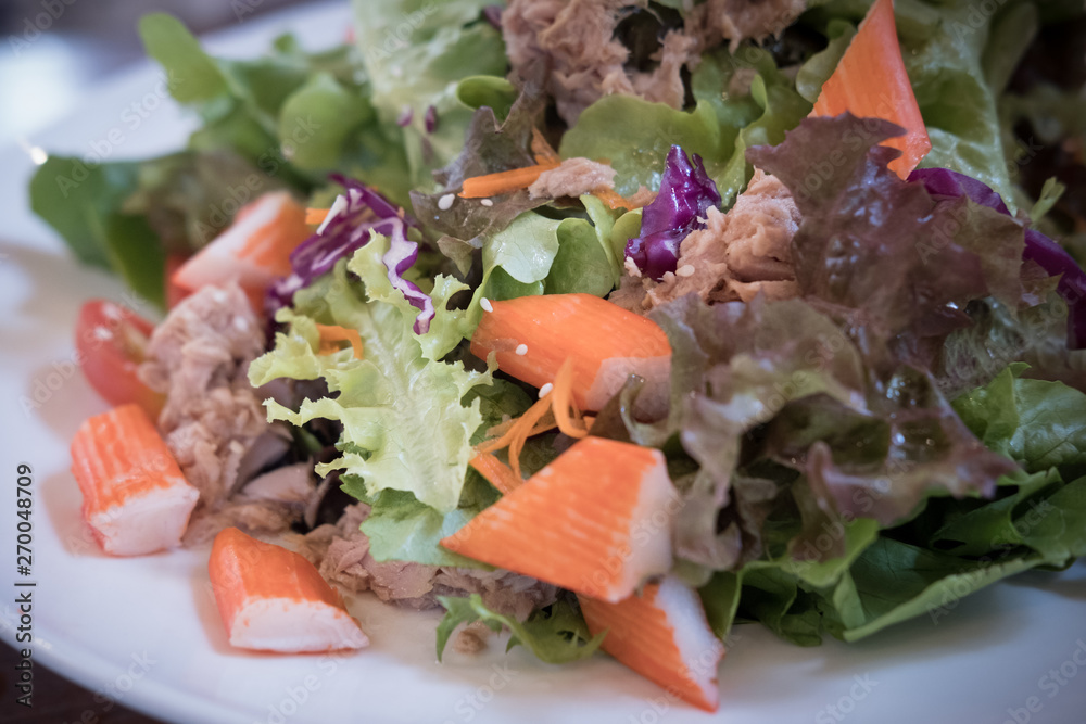 Healthy salad with fresh vegetables, crab stick and tuna
