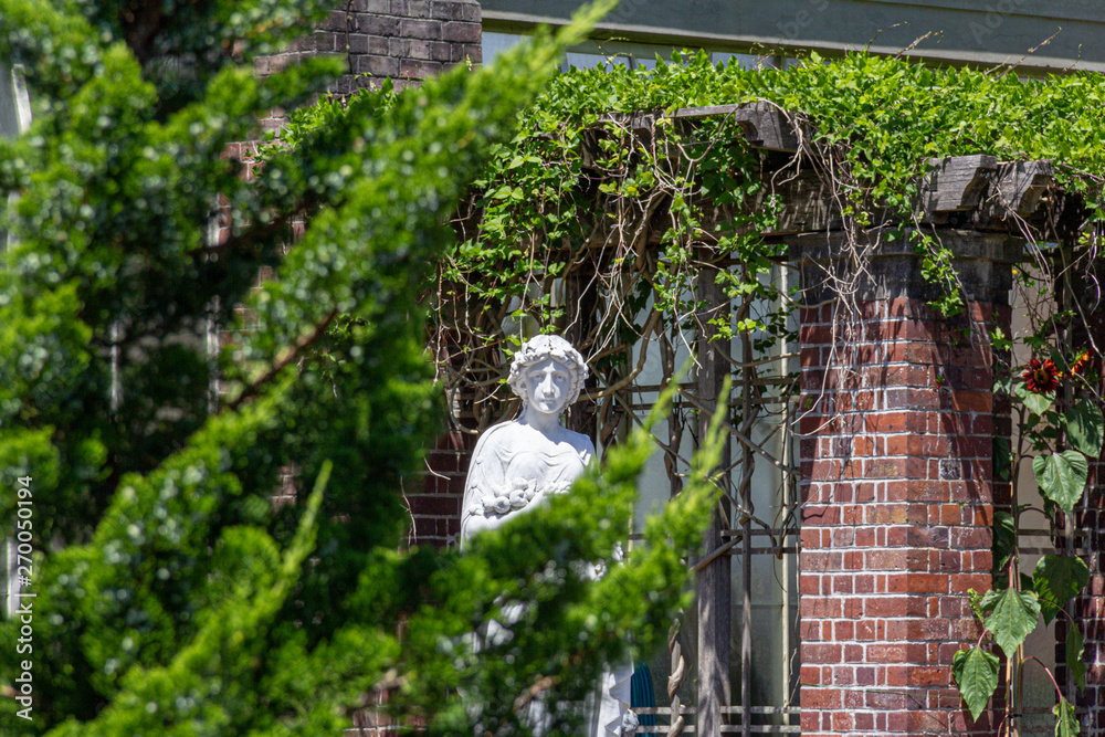 white statue peaking out from behind green branches