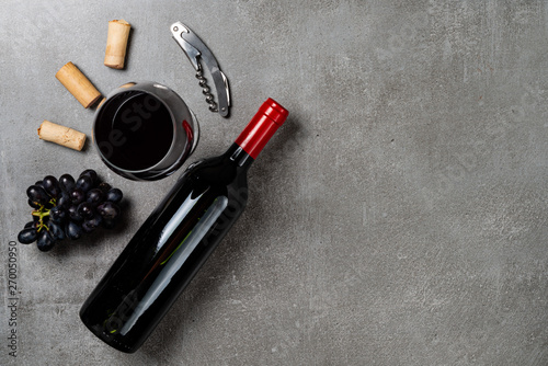 Bottle of wine, glass, corks, opener and grapes on concrete background. Copy Space.