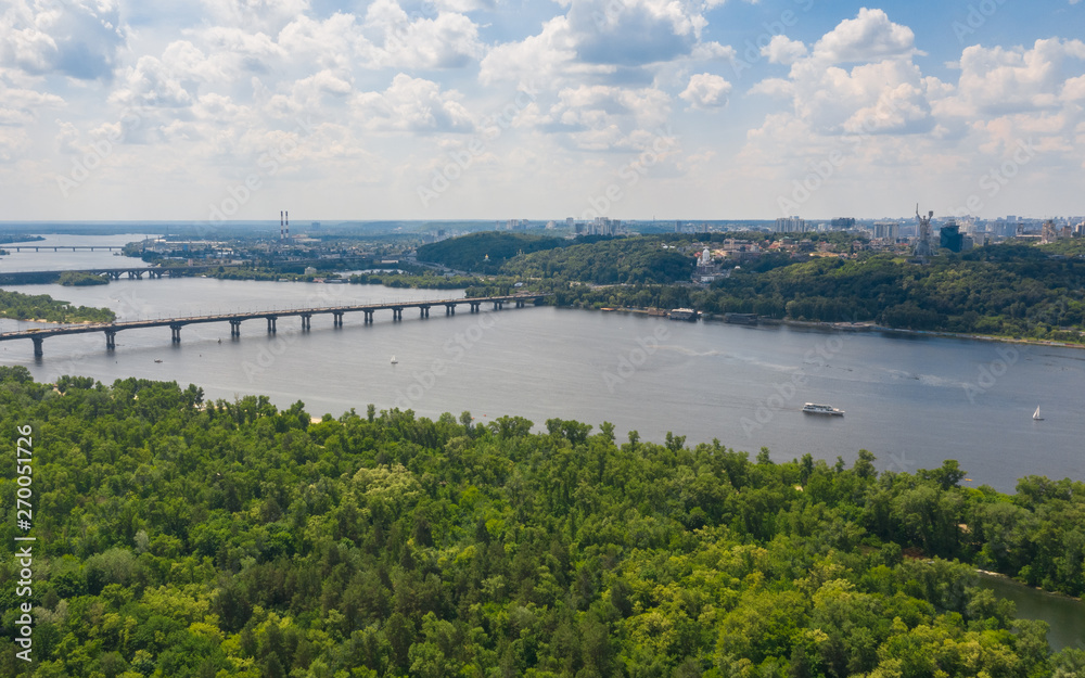 Aerial top view on road bridge across the Dnieper River in city at summer or spring time. Landscape and cityscape background. (Kyiv, Kiev) Ukraine.