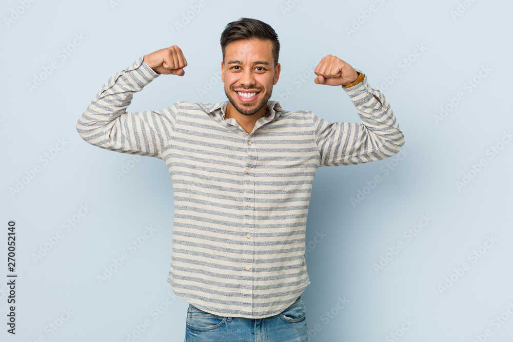 Young handsome filipino man showing strength gesture with arms, symbol of feminine power Young handsome filipino man showing strength gesture with arms, symbol of feminine power