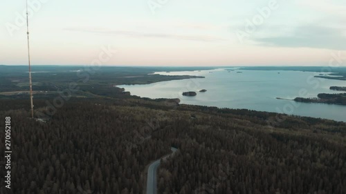 Aerial, pan, drone shot, of a radiotower, on the Vuokatinvaara hill and  Iso-sapsojarvi lake,on a sunny, spring day, in Vuokatti, Sotkamo, Kainuu, Finland photo