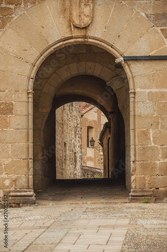 Arch gateway passing to an alley between gothic stone buildings in Plasencia © Celli07