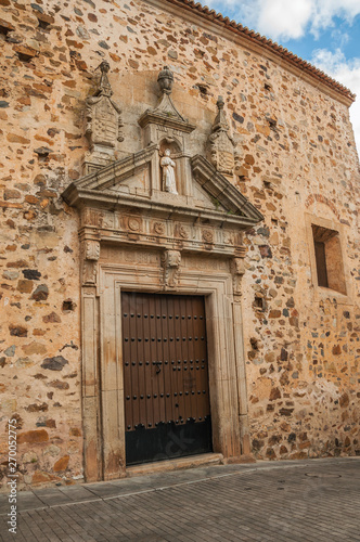 Wooden door with gothic decoration on stone building facade in Caceres