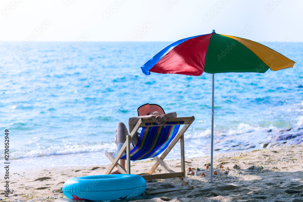 Summer vacation background with woman is sleeping on the beach bed on the beach in tropical weather.