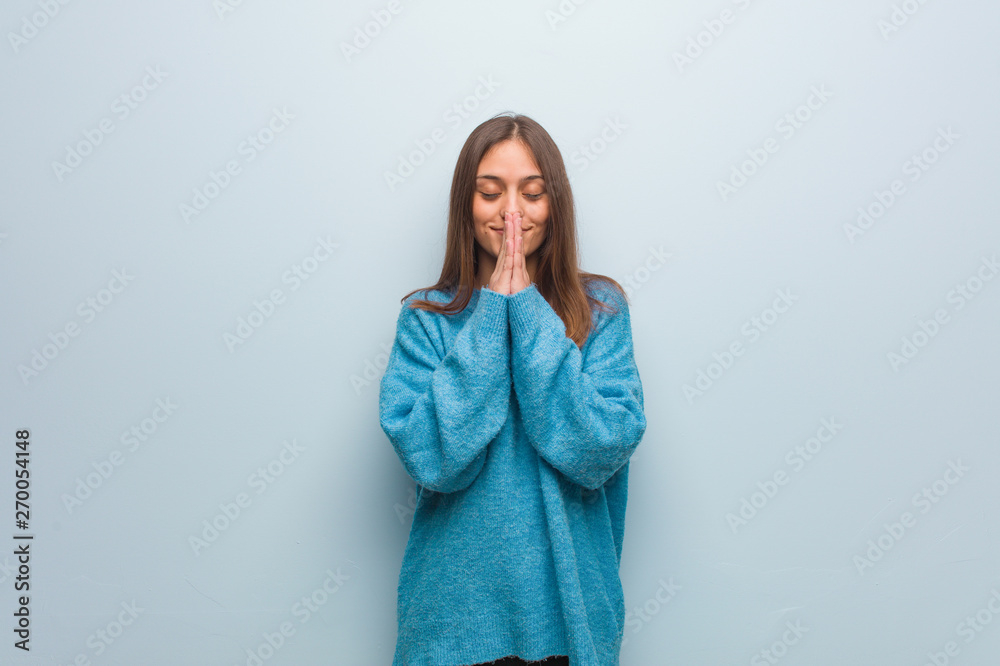 Young pretty woman wearing a blue sweater praying very happy and confident - obrazy, fototapety, plakaty 