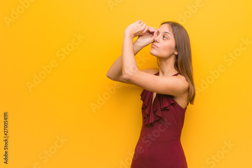 Young elegant woman wearing a dress making the gesture of a spyglass