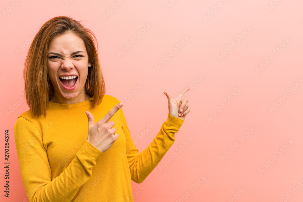 Young pretty young woman pointing with forefingers to a copy space, expressing excitement and desire. Young pretty young woman pointing with forefingers to a copy space, expressing excitement and desire.