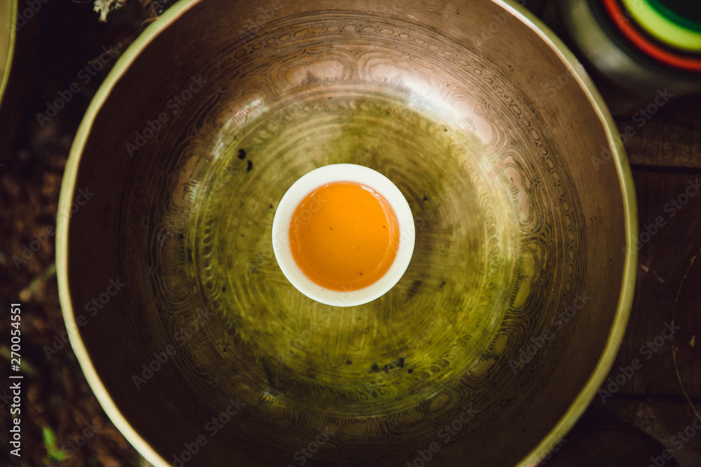 little white cup with tea in the Tibetan Singing Bowl. ceremony little white cup with tea in the Tibetan Singing Bowl. ceremony