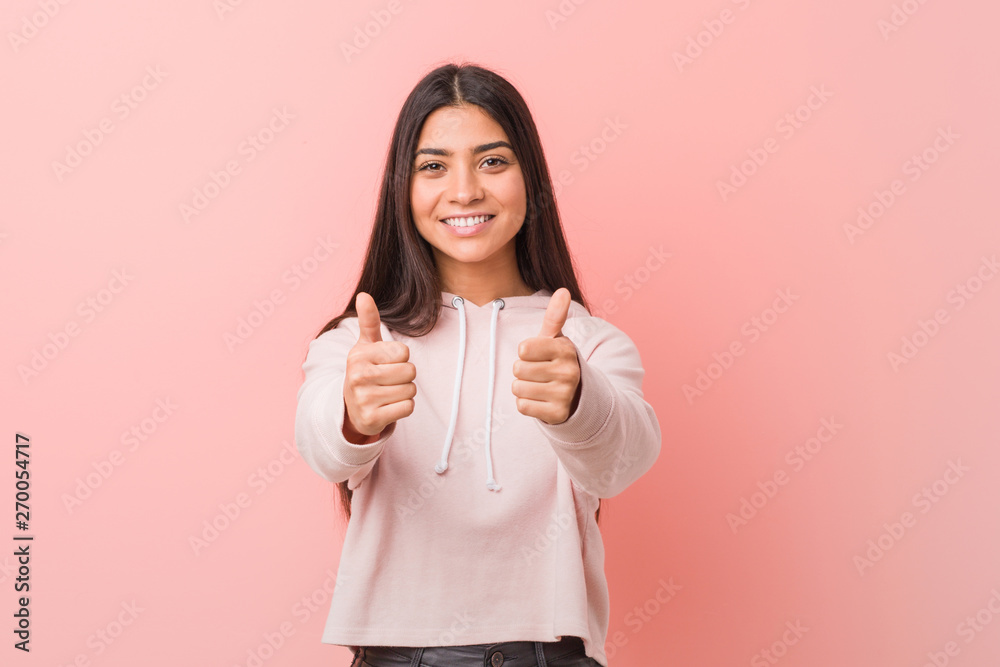 Young pretty arab woman wearing a casual sport look with thumbs ups, cheers about something, support and respect concept. Young pretty arab woman wearing a casual sport look with thumbs ups, cheers about something, support and respect concept.