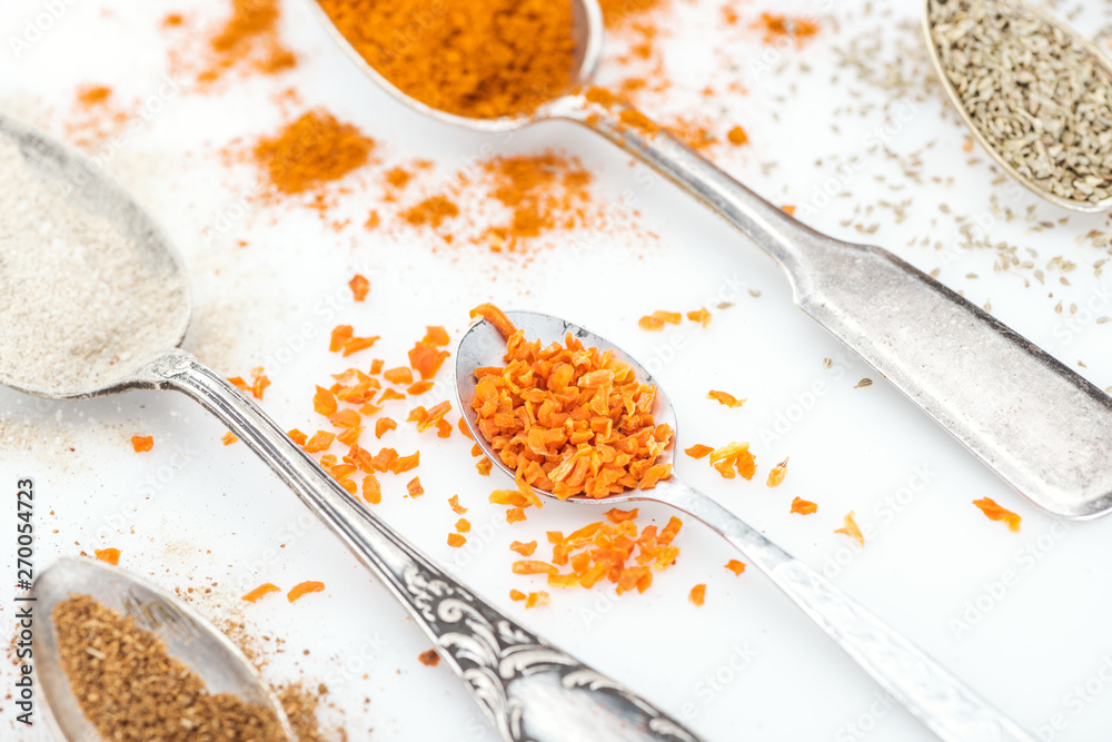 close up view of colorful spices in shiny spoons on white background close up view of colorful spices in shiny spoons on white background