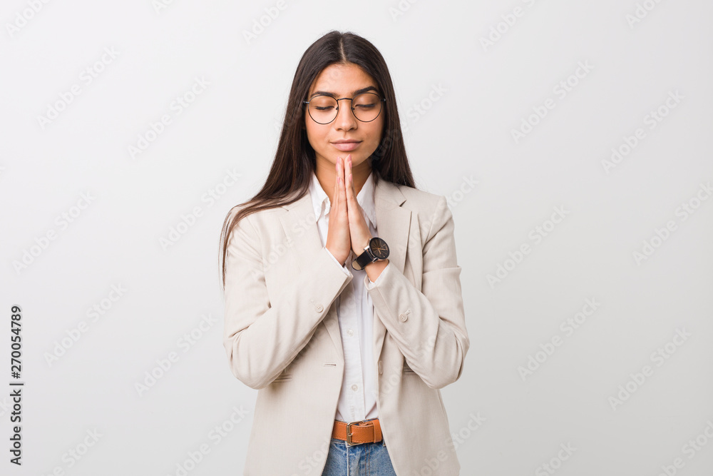 Young business arab woman isolated against a white background holding hands in pray near mouth, feels confident. Young business arab woman isolated against a white background holding hands in pray near mouth, feels confident.