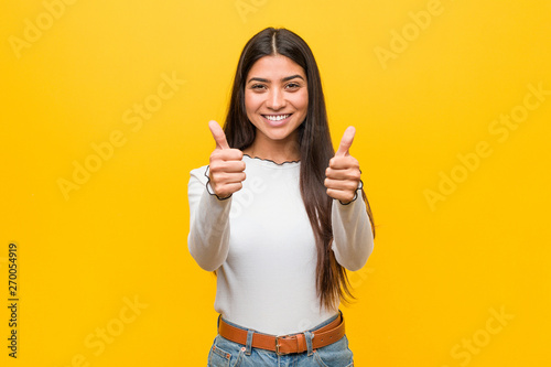 Young pretty arab woman against a yellow background with thumbs ups, cheers about something, support and respect concept.