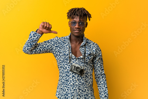 Young black rasta man wearing a vacation look showing a dislike gesture, thumbs down. Disagreement concept.