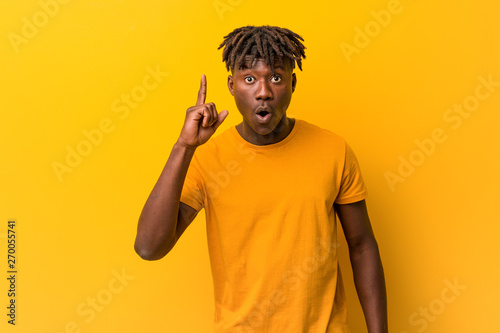 Young black man wearing rastas over yellow background having an idea, inspiration concept.