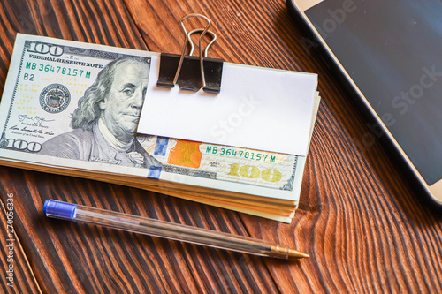 pack of dollars phone pen and paper sticker for your text on wooden background.