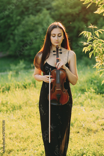 Beautiful girl with a violin on nature. long hair