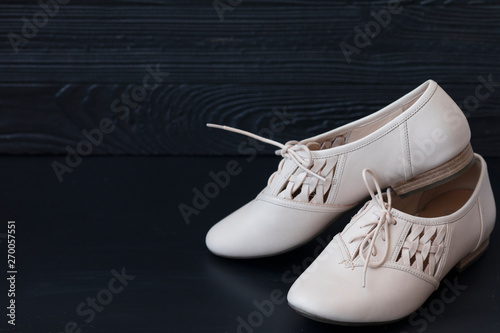 Pair of beige ladies flats shoes on dark wooden background