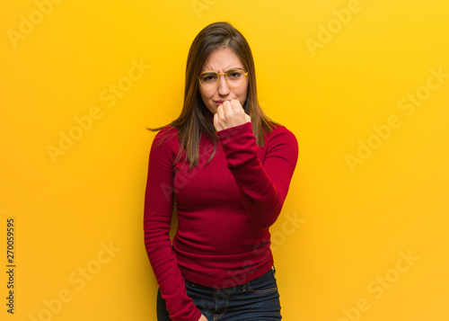 Young intellectual woman showing fist to front, angry expression © Asier