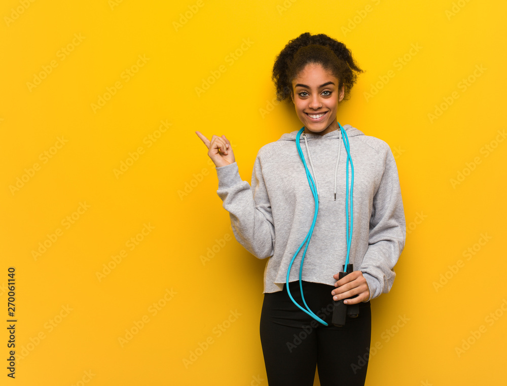 Young fitness black woman pointing to the side with finger. Holding a jump rope. Young fitness black woman pointing to the side with finger. Holding a jump rope.