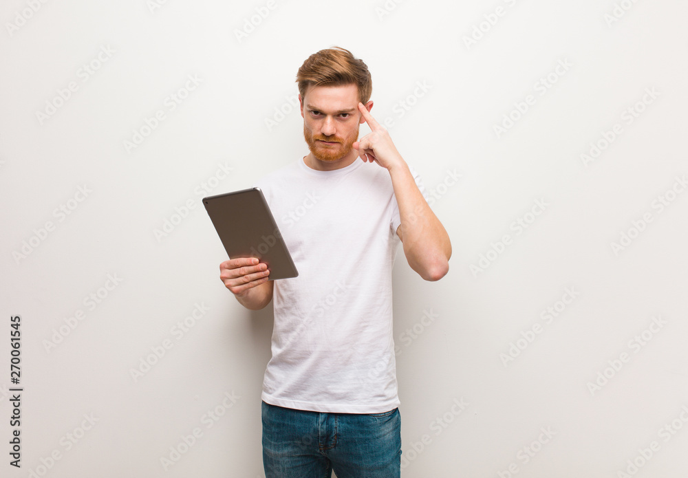 Young redhead man thinking about an idea. Holding a tablet. Young redhead man thinking about an idea. Holding a tablet.