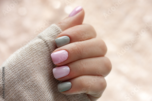 The pastel color manicure with the knitted sleeve of a brown sweater with glitter brown background