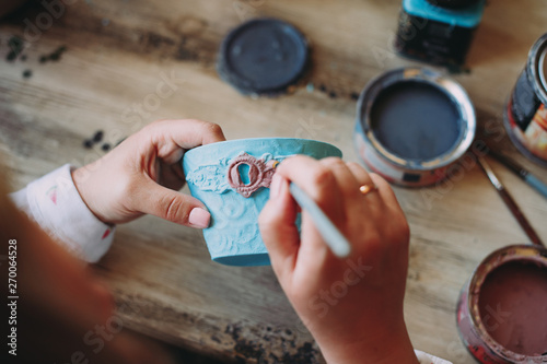 Woman working In her pottery studio. Ceramic workshop. Paint on clay cup in the pottery. Painting in pottery