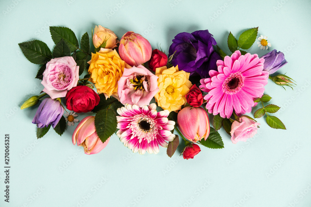 Creative layout made with beautiful flowers on blue background. Flat lay. Spring minimal concept