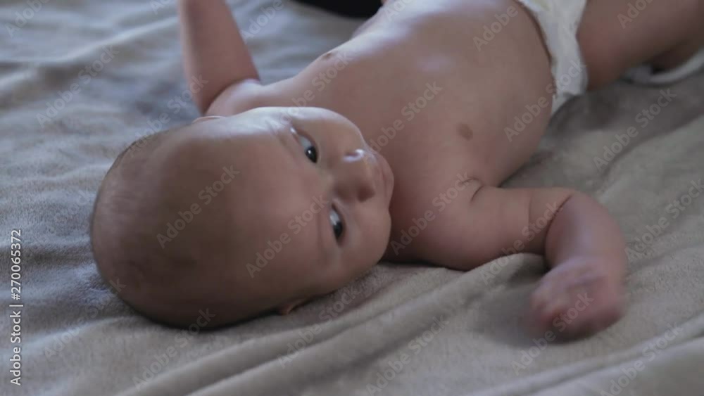 Pretty young mother dresses her little baby boy on the bed Pretty young mother dresses her little baby boy on the bed
