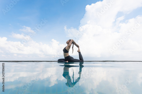 Fotografie Vacation of Attractive Asian woman relaxing in yoga king pigeon pose on the pool