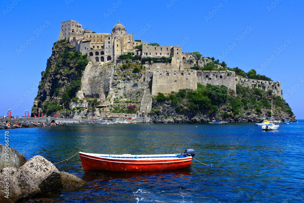Aragonese Castle with boat in the blue waters off the island of Ischia, Italy